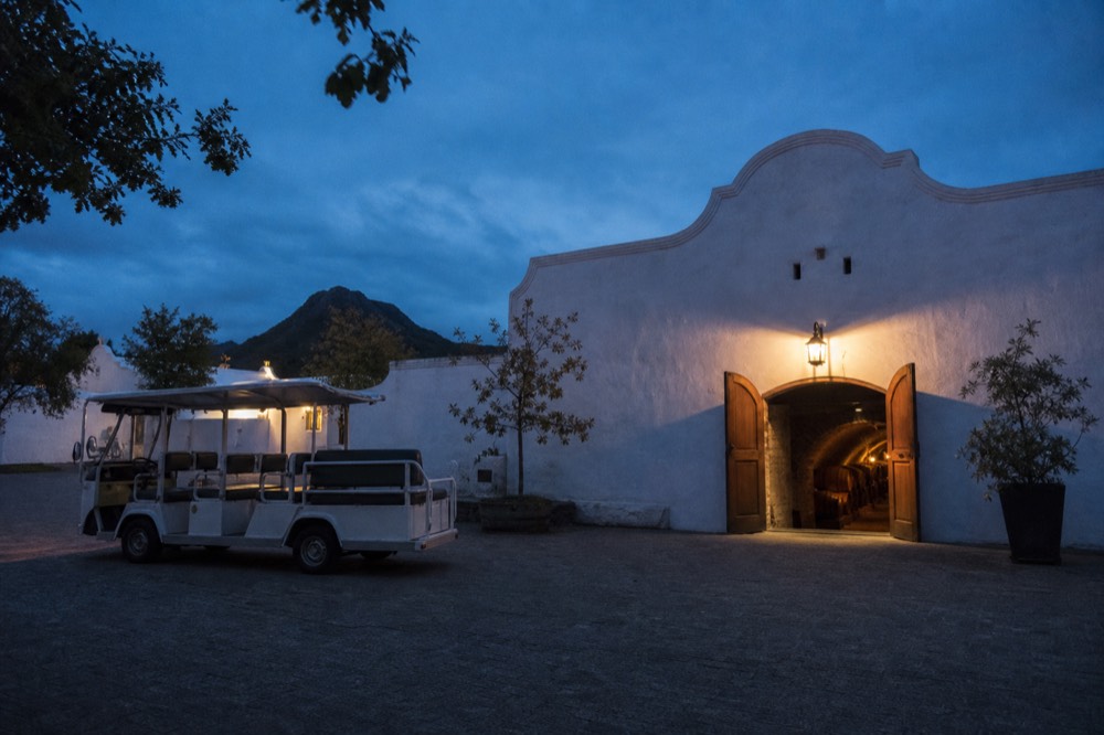 Small tour vehicle parked outside a Cape Dutch wine estate, no text, no logos, no people