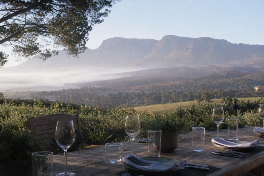 A table set for lunch overlooking vineyards and mountains, no text, no logos, no people
