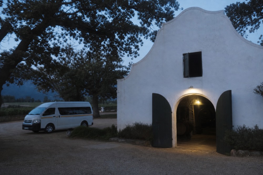 Guided tour minivan parked on a wine estate driveway with oak trees, no text, no logos, no people